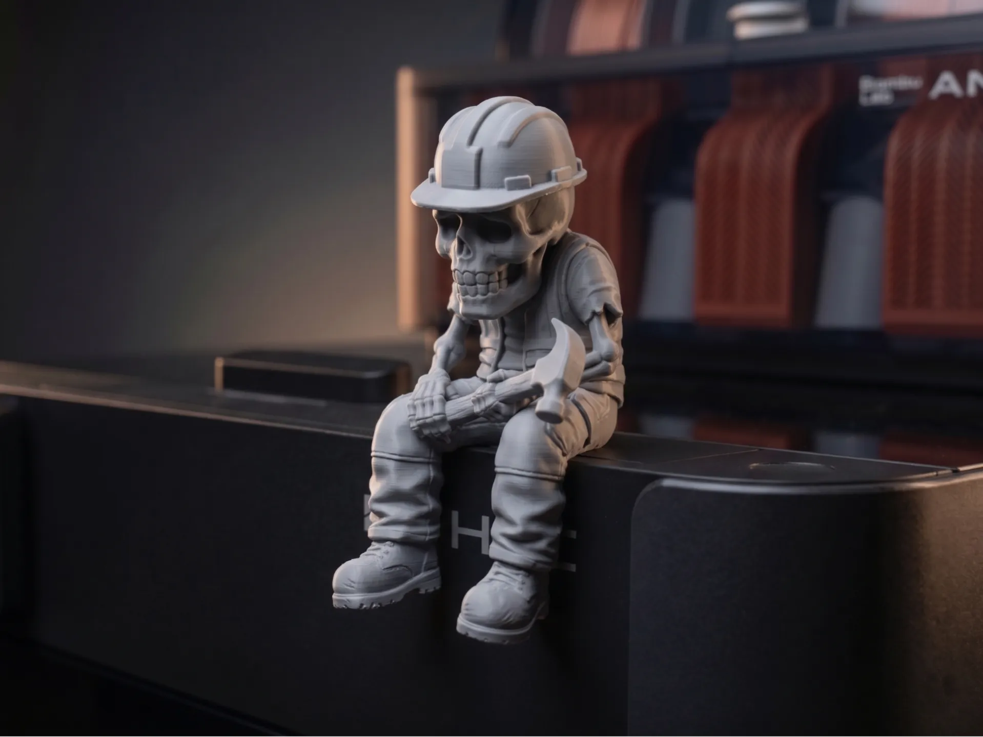 Skeleton in a hard hat and work clothes holding a hammer, sitting on a ledge