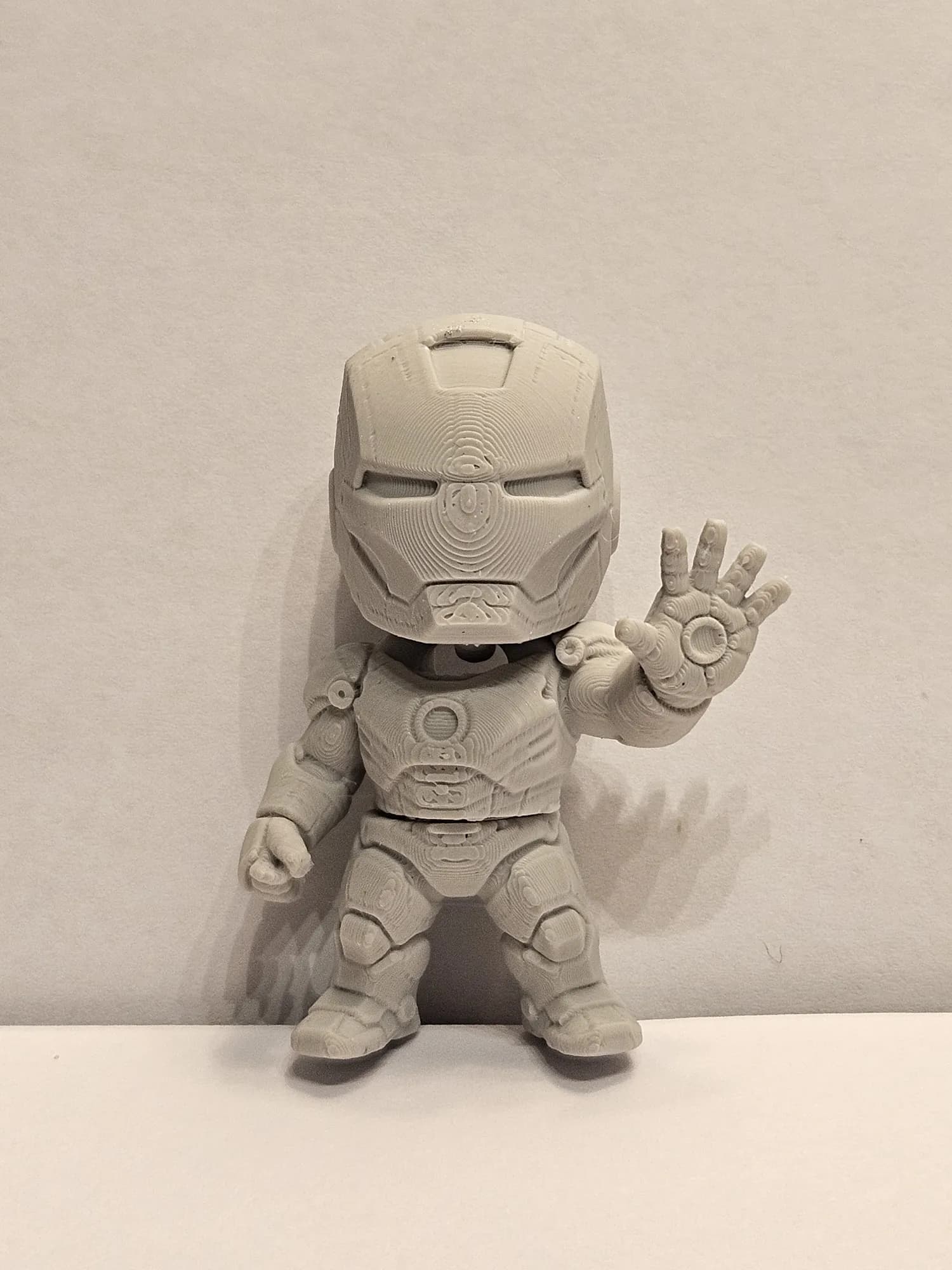 Chibi armoured figure printed in unpainted grey, one hand raised